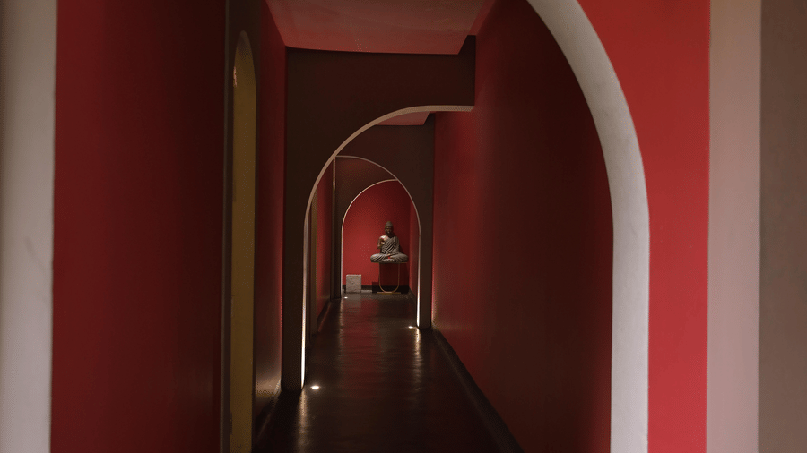A long red corridor with arched doorways at Hotel Sonar Bangla, Mayapur.
