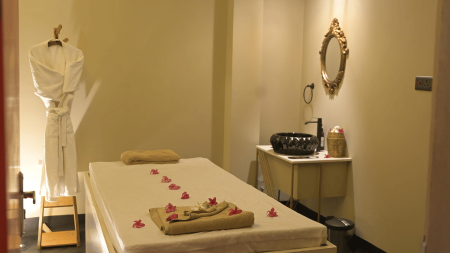 A spa room with a massage bed and soft lighting at Hotel Sonar Bangla, Mayapur.