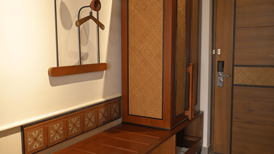  A wooden wardrobe and luggage bench located near the wooden entrance door of a guest room at Hotel Sonar Bangla, Mayapur.