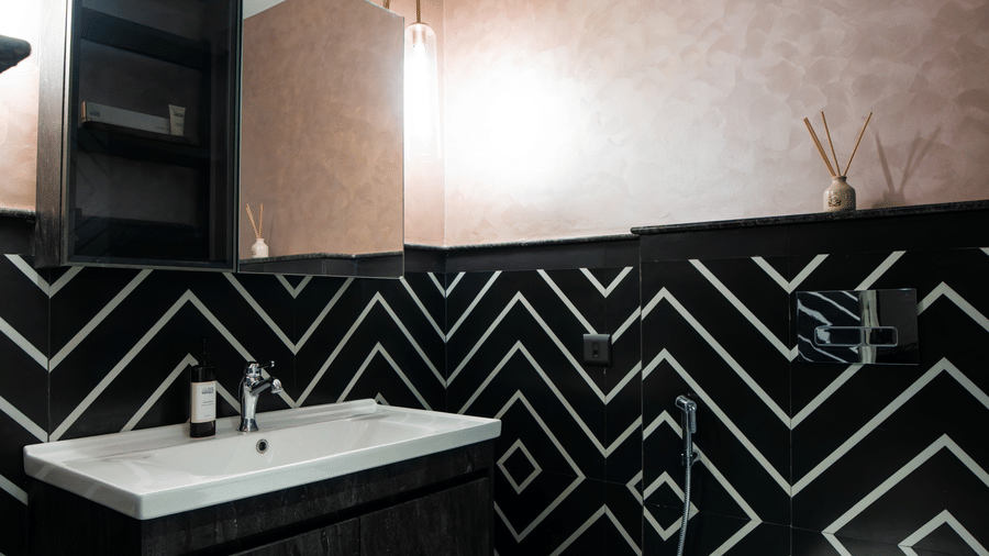 The contemporary bathroom inside the Super Deluxe Room featuring geometric black wall patterns, a vanity counter, and a toilet | Hotel Sonar Bangla, Susunia