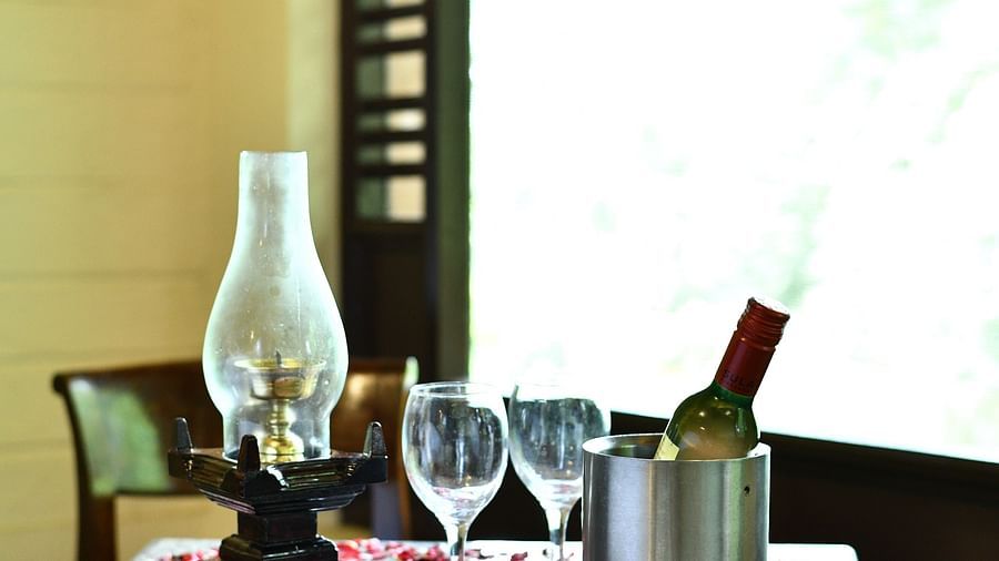 a beautifully decorated table with a wine bottle and an oil lamp at hoysala village resort, hassan