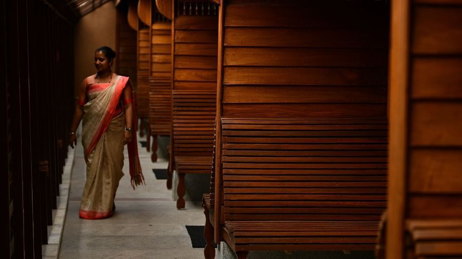 An image of a corridor with wooden benches on one side and wooden wall on the other - Hoysala Village Resort, Hassan