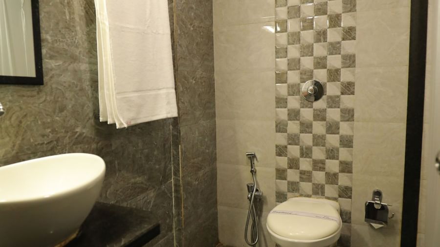 A well-maintained bathroom at Krushnai Resort with a sink, mirror, and a western commode.