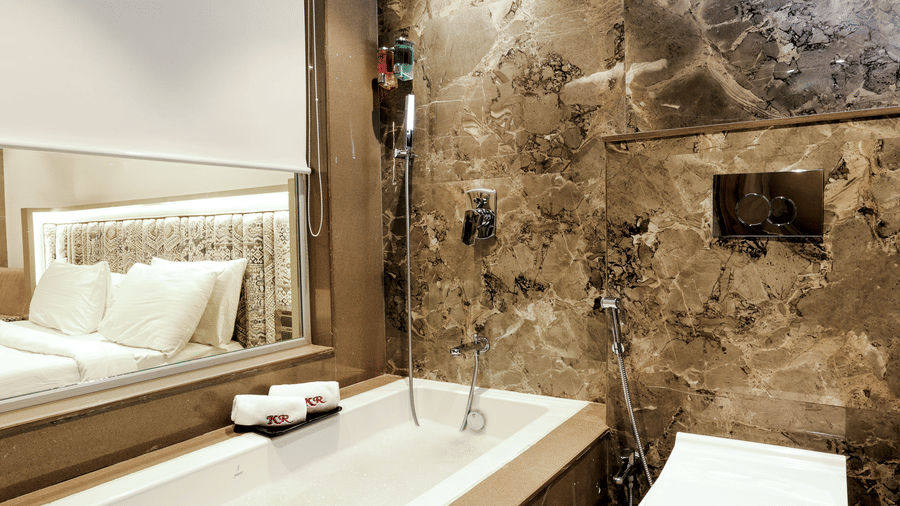 Close-up view of a modern bathroom vanity with a large mirror and textured wall panelling at Kumar Resort by Turtle.