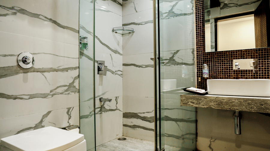 Spacious bathroom with a glass shower enclosure and toilet at Kumar Resort by Turtle.