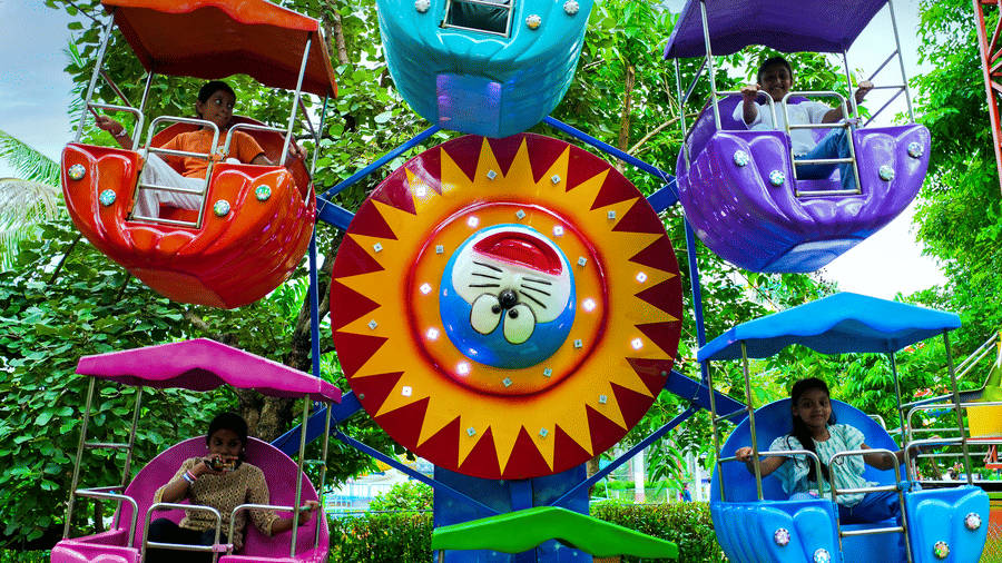 A playful spinning ride shaped like vibrant sea creatures, displayed against a backdrop of greenery.