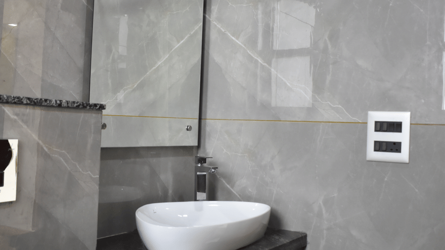 Modern bathroom vanity unit with a white ceramic basin, dark wooden cabinet, and large mirror.