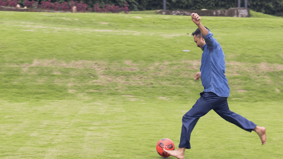A person in a blue top and trousers is playing on a grassy, outdoor pitch - Megha Resort & Villas, Dehradun