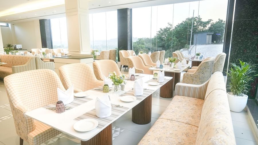 A portrait of a dining table with chairs arranged on one side and a large sofa on the other - NAMAMI BY ZENQ BANKHANDI