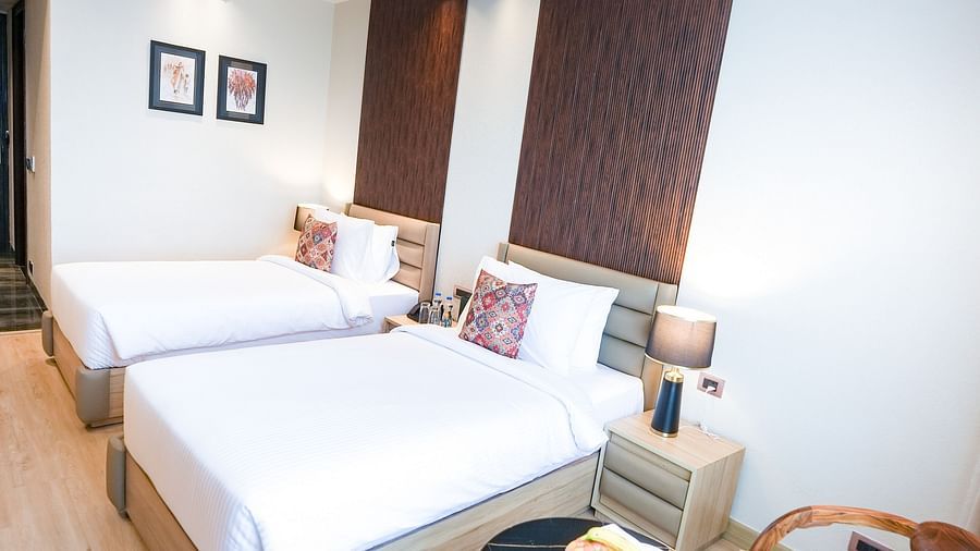 A portrait image of a hotel room in Bankhandi that features a twin bed a coffee table and cosy cushioned chairs - NAMAMI BY ZENQ BANKHANDI