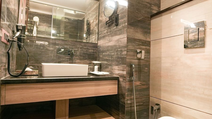 An image of a modern bathroom in our Superior Temple View Room with a commode, a wall mounted mirror and a large sink - NAMAMI BY ZENQ BANKHANDI