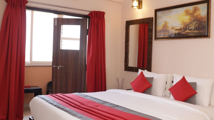 A bed near a window with curtains, wall art, bedside tables and ceiling fan at Nazri The Verda Hotel, Arambol.