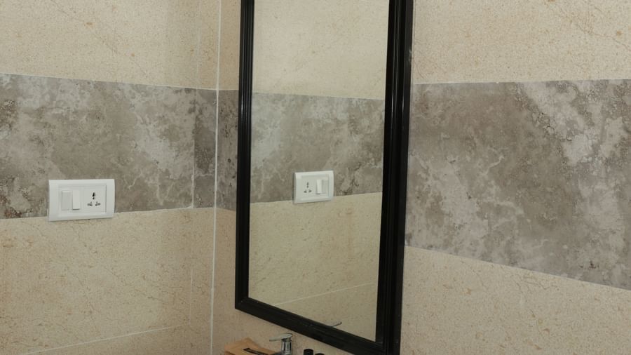 A washbasin with a mirror and wall-mounted light in the bathroom at Nazri The Verda Hotel, Arambol.