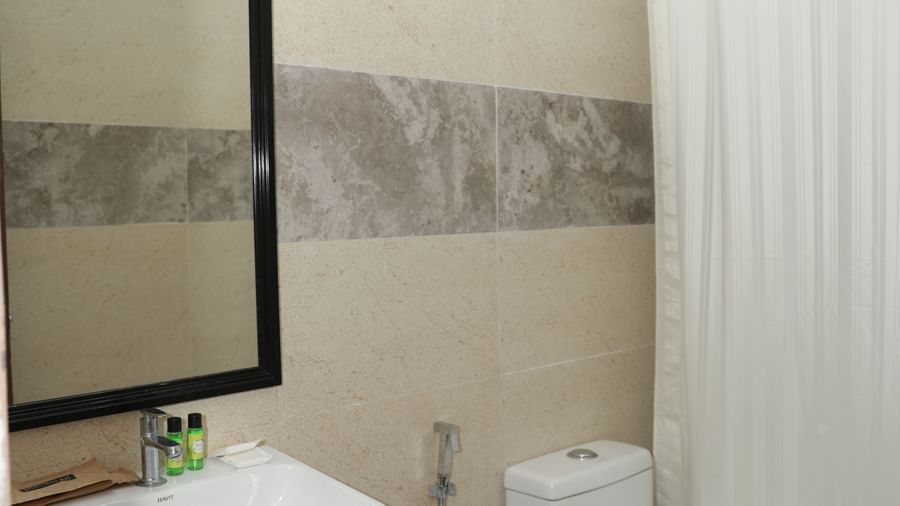 A bathroom with a washbasin, mirror, toilet and shower curtain at Nazri The Verda Hotel, Arambol.