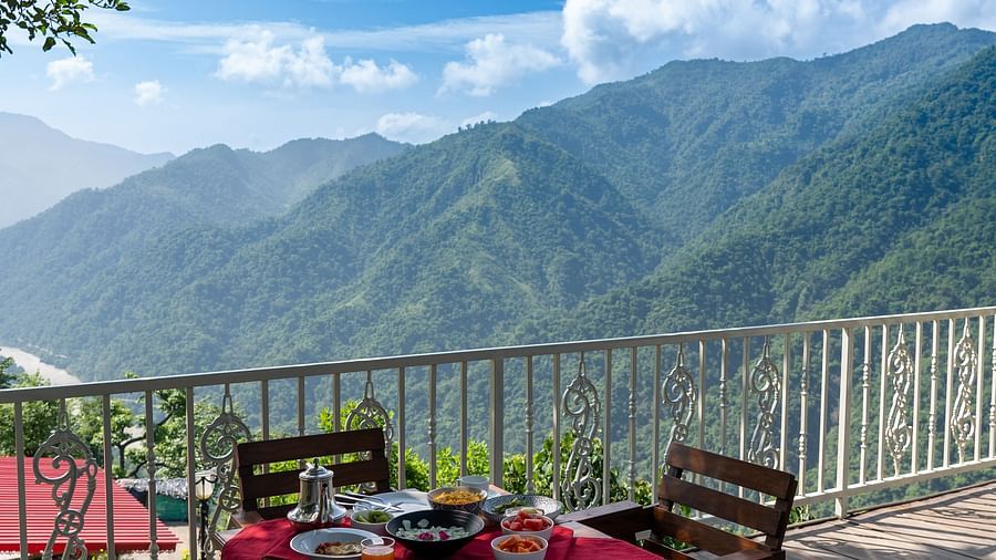 open sitting area with tables in chairs with mountains in the backdrop at Neer Ganga Resorts