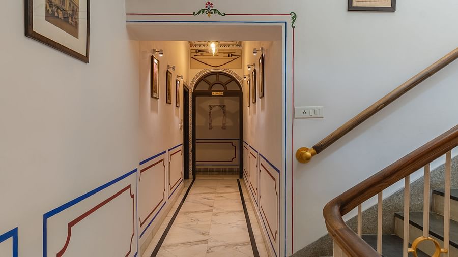 A corridor pathway with wall-mounted frames and a staircase on the side | Panna Vilas Udaipur