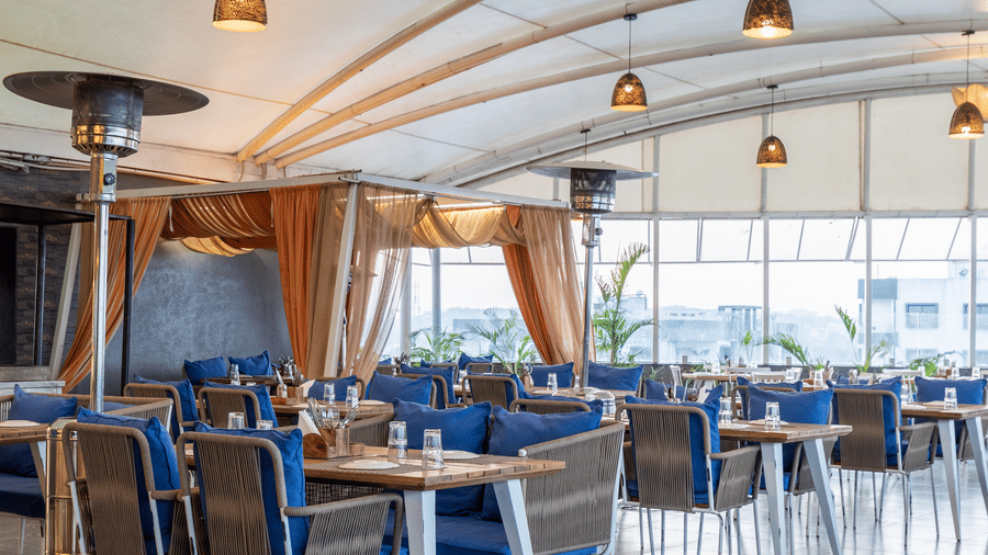 Elegant indoor seating area of Nazaara Restaurant , Papaya Tree Hotels, with neatly arranged tables and ceiling lights creating a cosy dining space.
