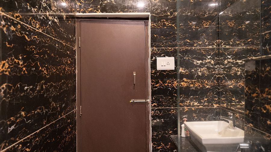 Image of a washroom with a door at the corner and a sink and toilet on the side at Parampara Resort & Spa, Kushalnagar.