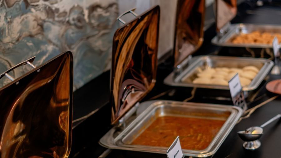 Extensive buffet setup along a wall with multiple food stations | Pravasa Hotel, Vijayapura