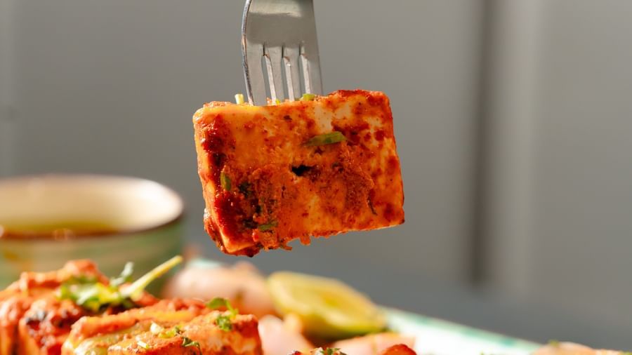 Fork lifting a piece of paneer tikka from a platter of grilled items | Pravasa Hotel, Vijayapura