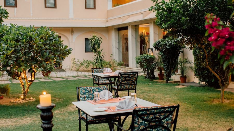 A garden area with outdoor seating and flowers on the grounds of Royal Heritage Haveli.