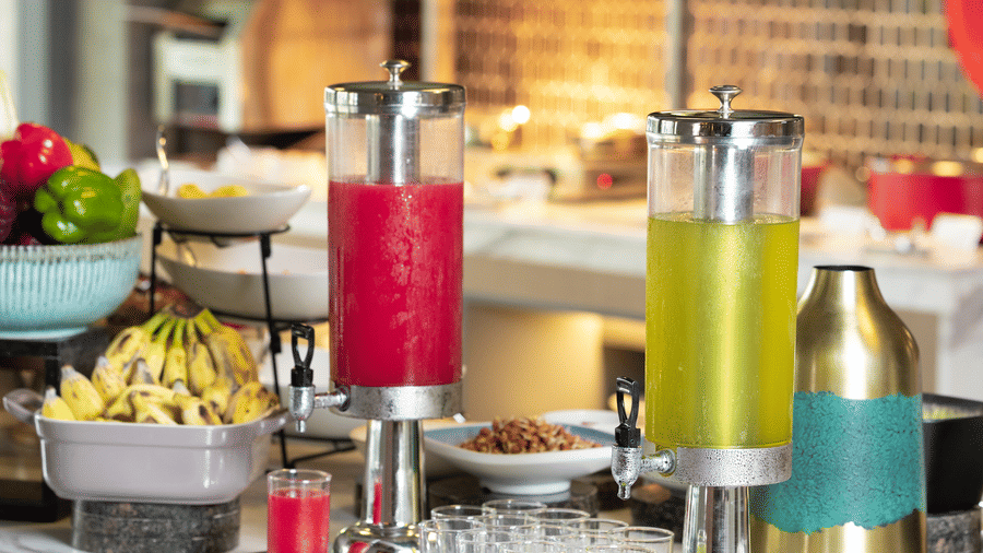 2 glass dispensers filled with red and yellow fruit juices on a marble breakfast counter at Sands Point Hotel, Pondicherry.