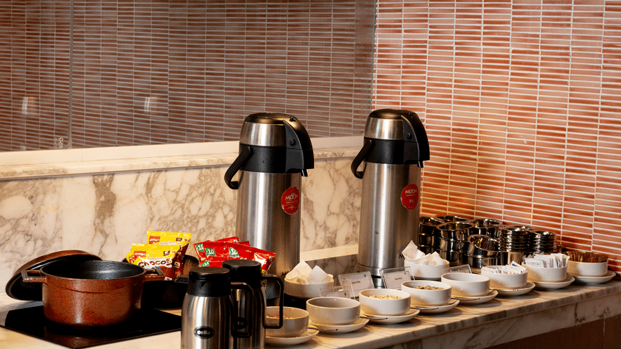 A dedicated beverage counter featuring 2 large silver thermal coffee dispensers at Sands Point Hotel, Pondicherry.
