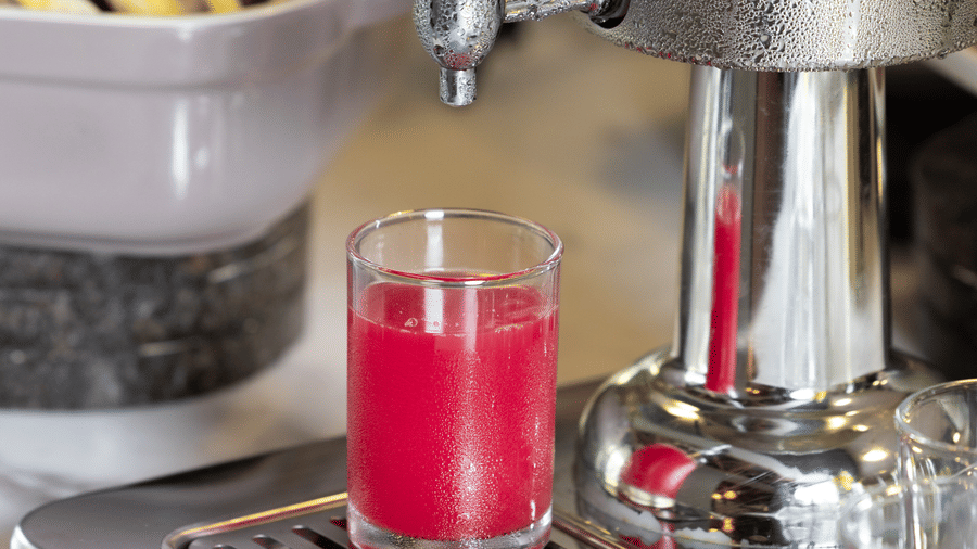 1 glass being filled with chilled watermelon juice from a stainless steel dispenser at Sands Point Hotel, Pondicherry.