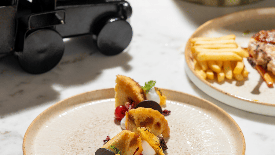 A white plate presenting 1 artistic arrangement of fruit-topped pastries at Sands Point Hotel, Pondicherry.