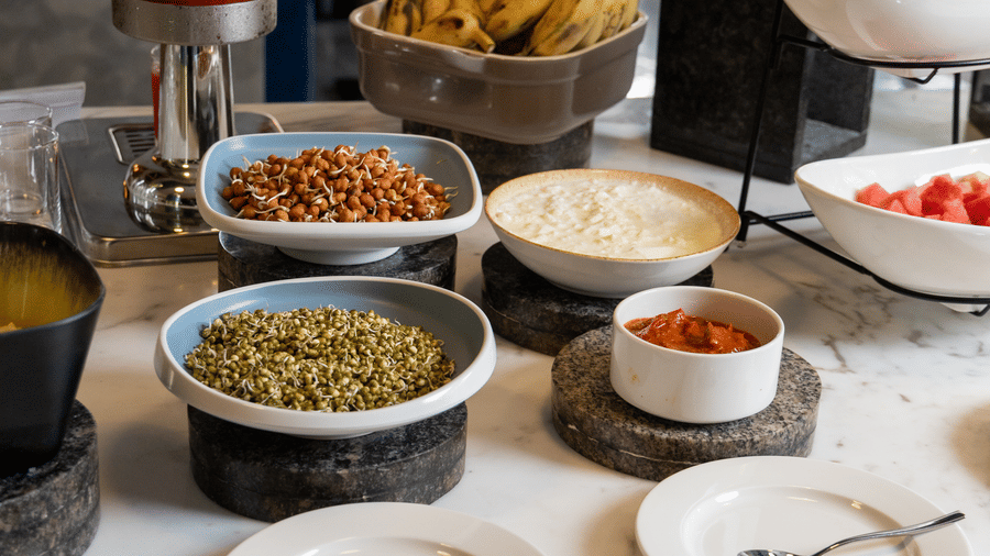 A breakfast station featuring 1 large juice dispenser and various salad bowls at Sands Point Hotel, Pondicherry.