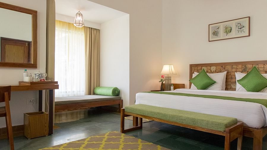 A room at Saraca Resort & Spa Corbett with a double bed, a work desk and chair and a chandelier hanging from the ceiling