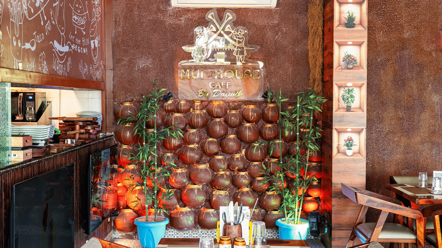 Light-filled restaurant interior with large windows overlooking greenery, modern wooden tables and chairs.