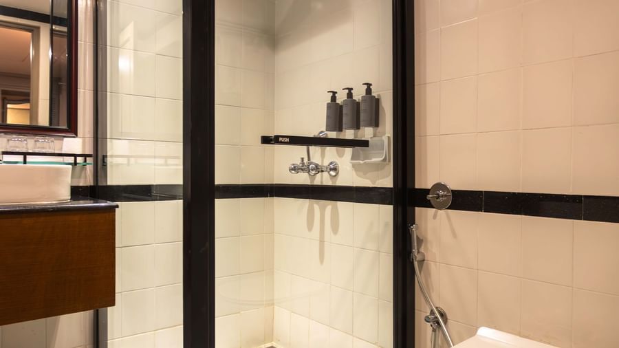 A compact bathroom at Shilton International, Kochi, featuring a modern shower enclosure and essential fixtures.