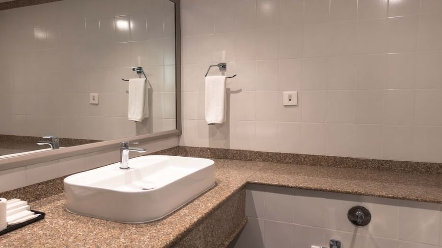  A washroom at Shilton International, Kochi, with a large mirror, vessel sink, and ample counter space.