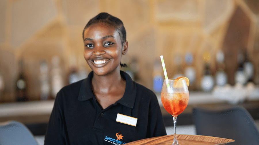 View of a woman holding a drink on a serving tray at Shooting star Boutique Hotel