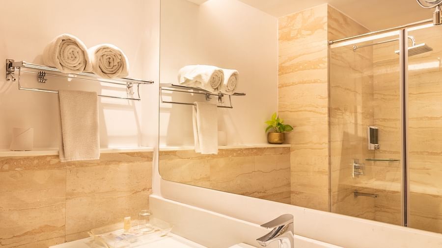 A narrow view of a bathroom with a sink, a mirror, and lighting in Superior Room- TGI Grand Fortuna, Krishnagiri Main Road, Hosur