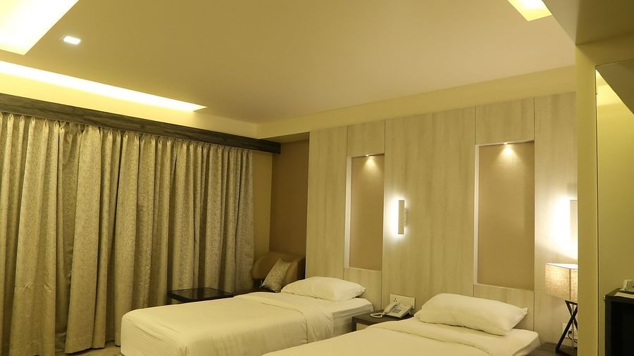 Executive Room with a vanity area, including a mirror and a sink, illuminated by warm lighting, with a chair and beige wall visible.