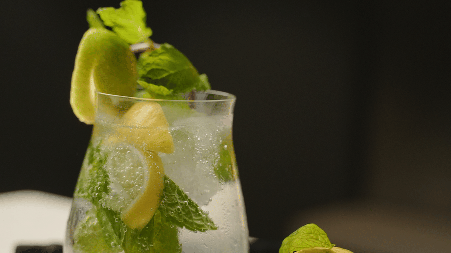 Refreshing cocktail garnished with lime and herbs, elegantly presented at Trino Bar