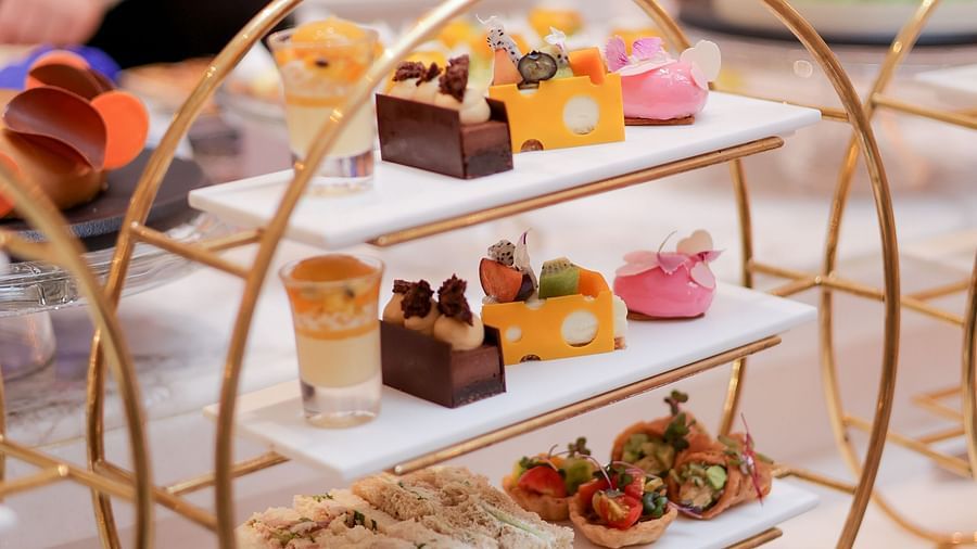 Image featuring a luxurious afternoon tea setup with a gold-tiered stand of assorted pastries