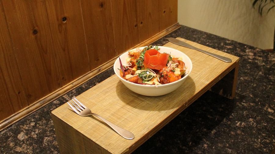 Side angle of a salad bowl on a wooden tray against a wooden-panelled wall at Dagshai Manor Kasauli - Inde Hotels.