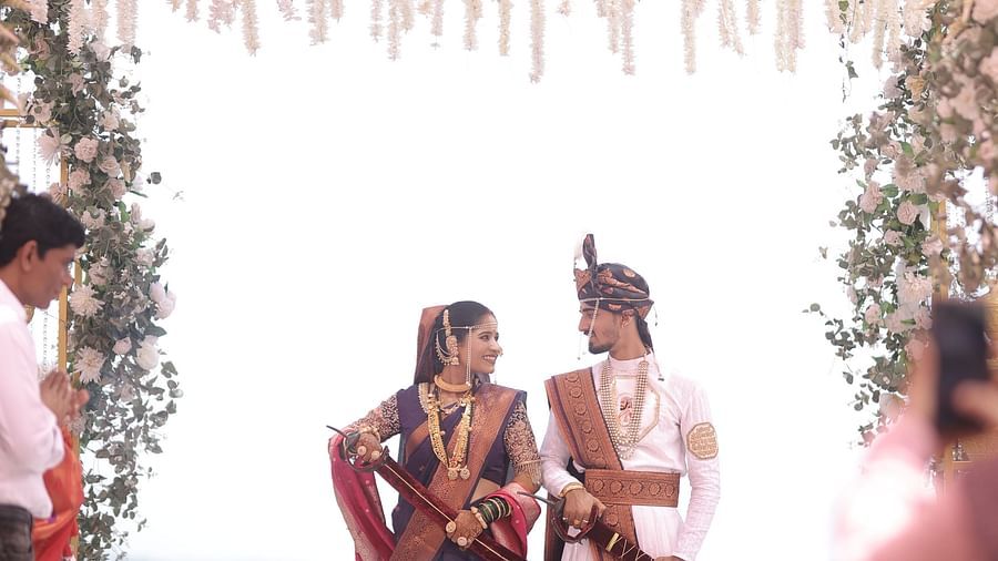 A newlywed couple sits together on a decorated platform, likely during their wedding reception. Floral arrangements enhance the celebratory atmosphere - The Grand Legacy Resort and Spa