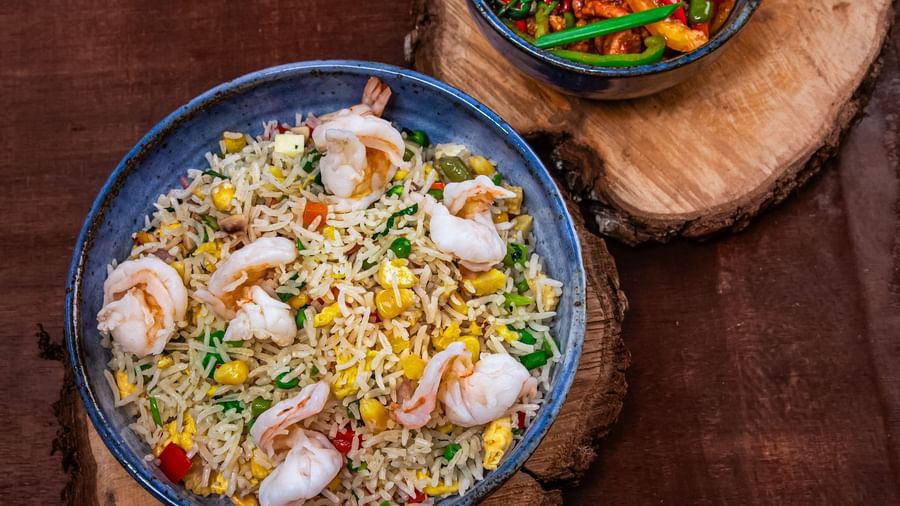 A bowl of a dish with vegetables and herbs, served alongside a small bowl of chili salad on round wooden mats, garnished with green chilies on a dark wooden surface at The Hamuse Hotel, Kodaikanal .