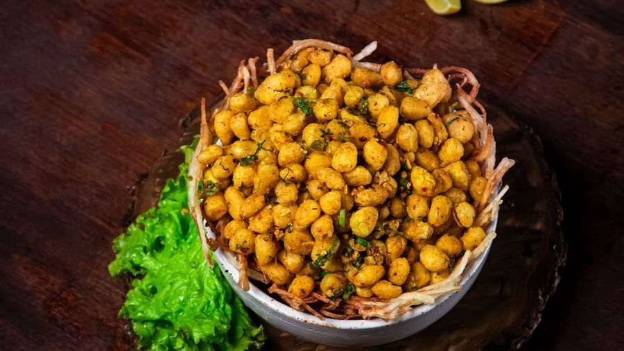  A bowl of appetiser garnished with herbs, served on a wooden platter with lettuce and lime wedges on a rustic wooden table at The Hamuse Hotel, Kodaikanal.
