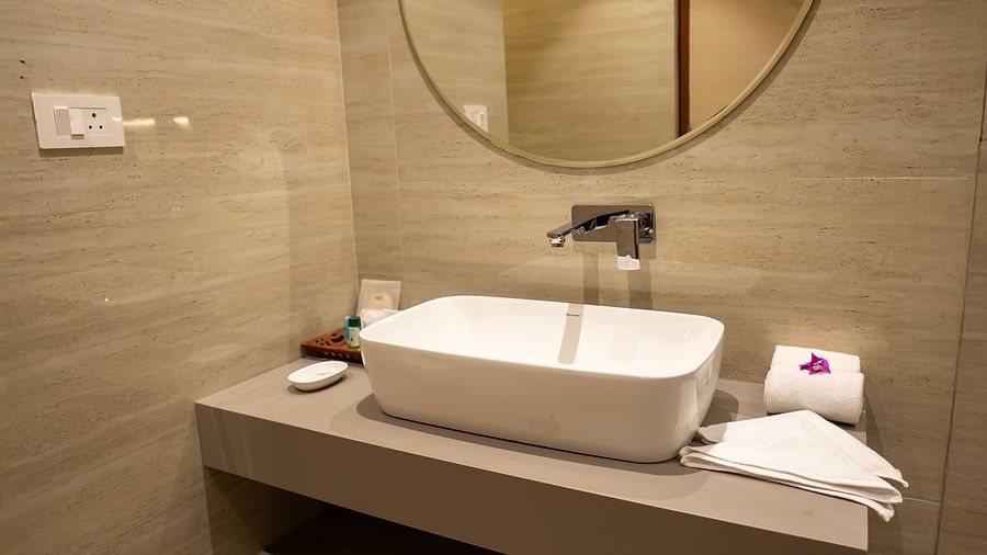 A wash basin with a circular mirror above it in the Garden Courtyard room at The Shore Trishvam.