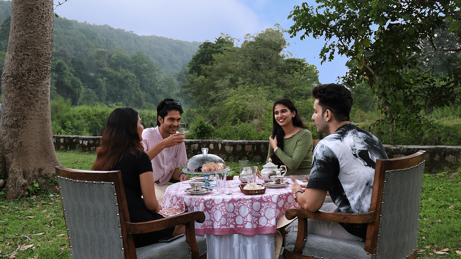 A lavish open-air dining setup with people enjoying a meal during the day at The Sylvan Retreat, Dehradun.