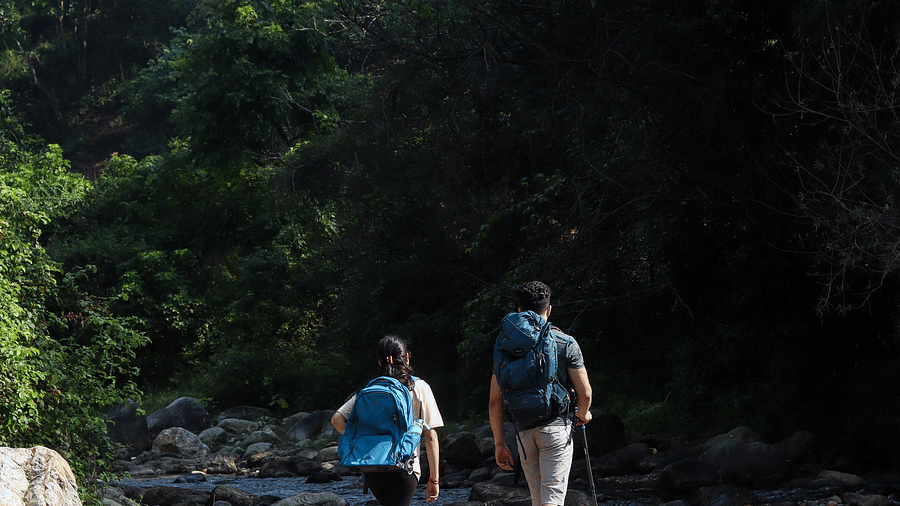 Two people hiking alongside a water stream at the Sylvan Retreat, Dehradun.