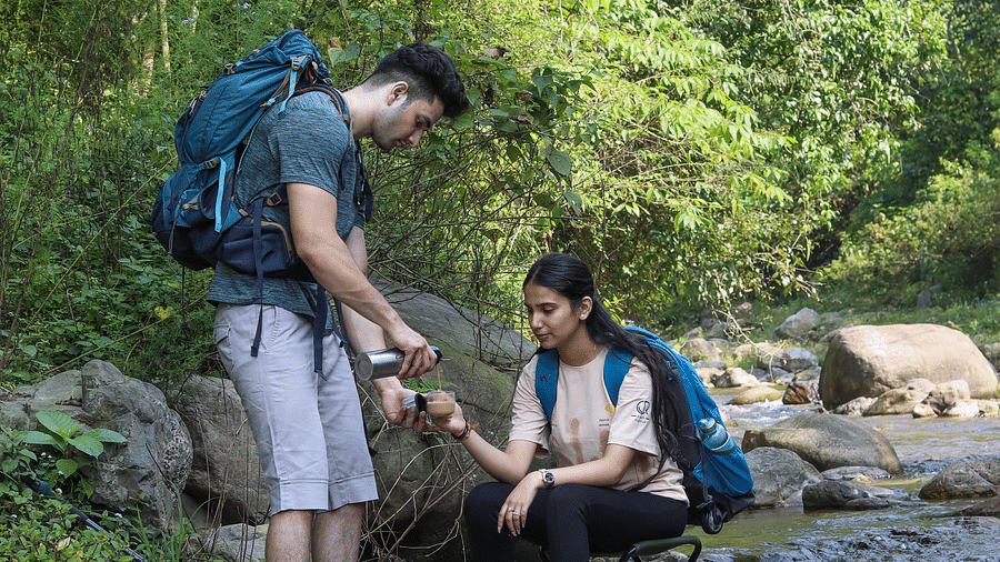 Two people resting on a rock alongside a water stream at the Sylvan Retreat, Dehradun.