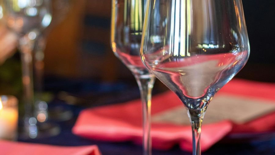 Close-up of wine glasses on a table set with red napkins and golden spoons against a blue tablecloth