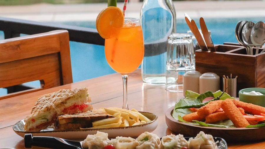 Refreshing orange drink and sandwiches served at a poolside dining table at The Verda de Miranda Resort.
