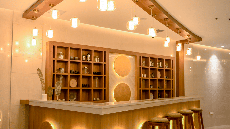 A bar counter with wooden bar stools and shelves at Tiara by MPS.